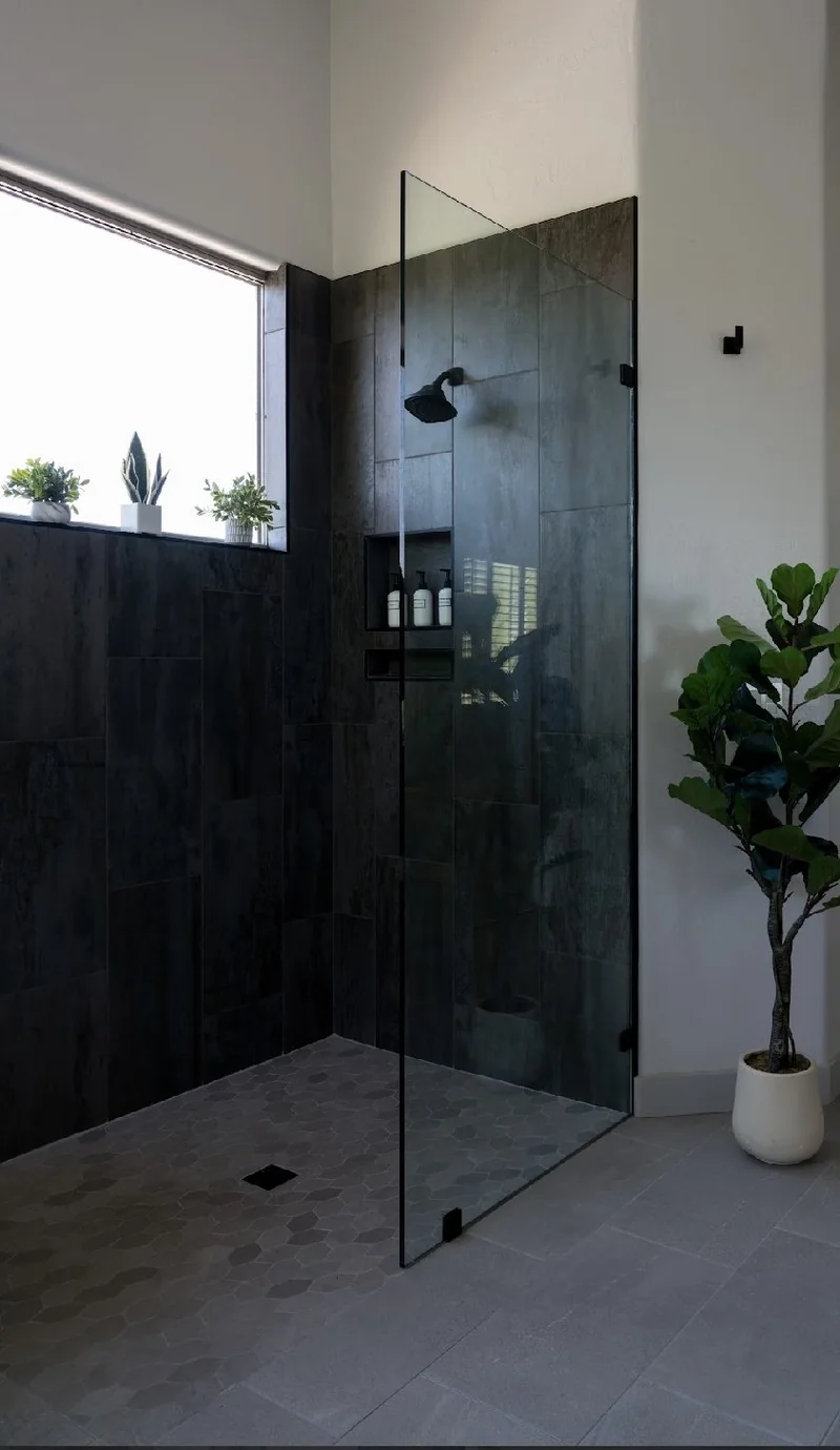 Finished walk-in shower with dark tile, glass panel and hexagonal floor tile in a Phoenix bathroom remodel